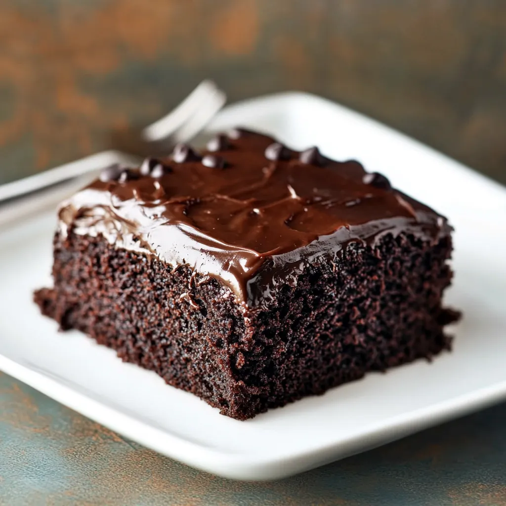 A slice of rich chocolate cake served on a simple white plate.