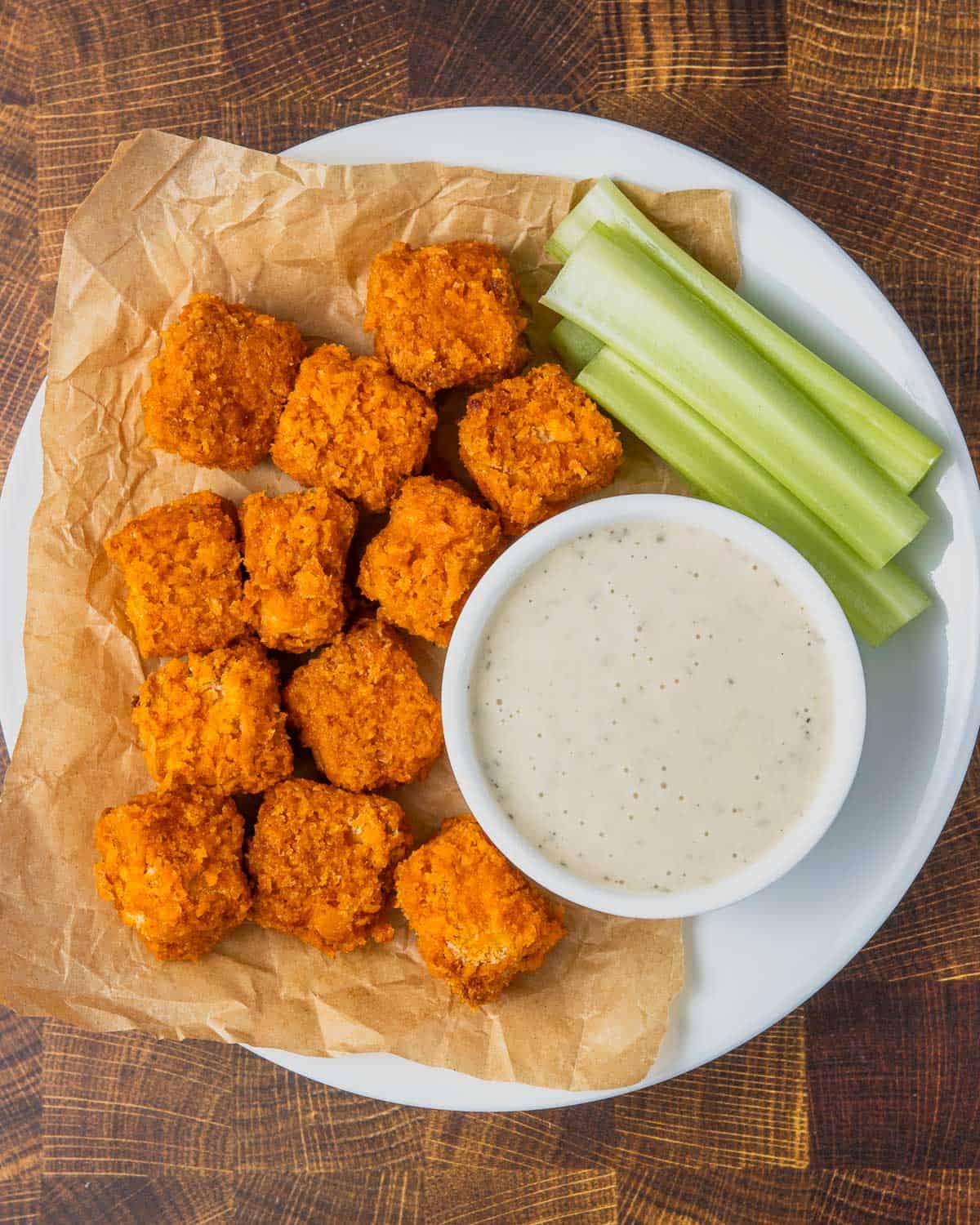 A plate of food with a bowl of sauce and celery.