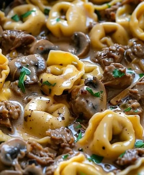 A bowl of pasta with mushrooms and meat.